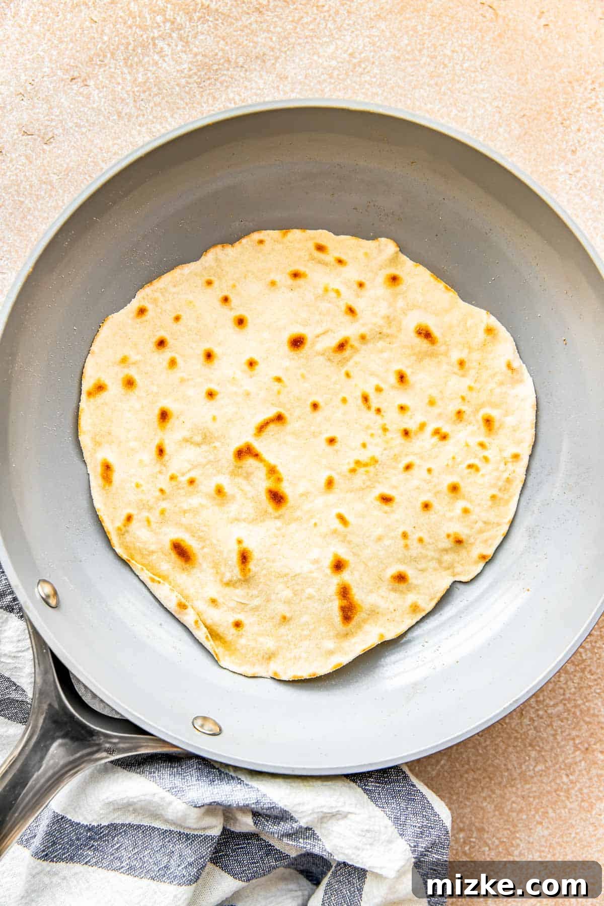 Craft Your Own Perfect Flour Tortillas 8 A freshly cooked flour tortilla with beautiful golden-brown spots, resting in a nonstick skillet after being flipped.