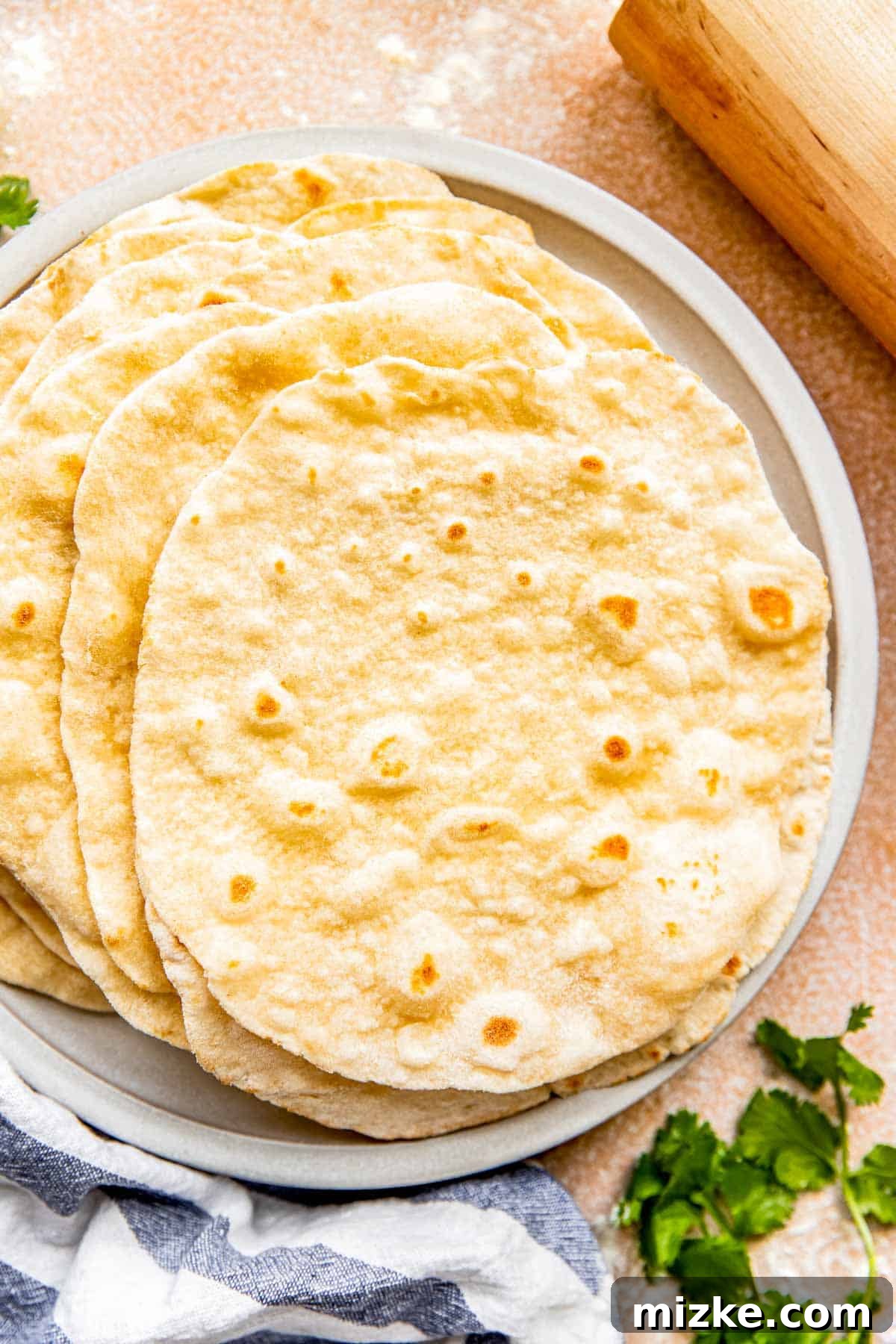 Craft Your Own Perfect Flour Tortillas 9 A comforting image of a stack of warm, homemade flour tortillas on a ceramic plate, nestled beside a striped linen towel.