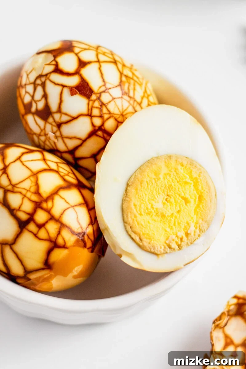 Taiwan's Fragrant Marbled Eggs 6 Halved Taiwanese tea eggs all peeled in a white bowl with cooked egg yolk exposed.