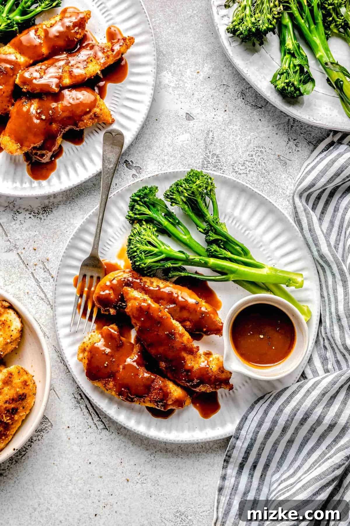 Experience the delightful fusion of textures and flavors in this bourbon chicken, featuring crispy chicken and an unparalleled sweet and savory sauce. A plate of homemade bourbon chicken served with a side of vibrant green steamed broccoli, extra sauce, and a fork.