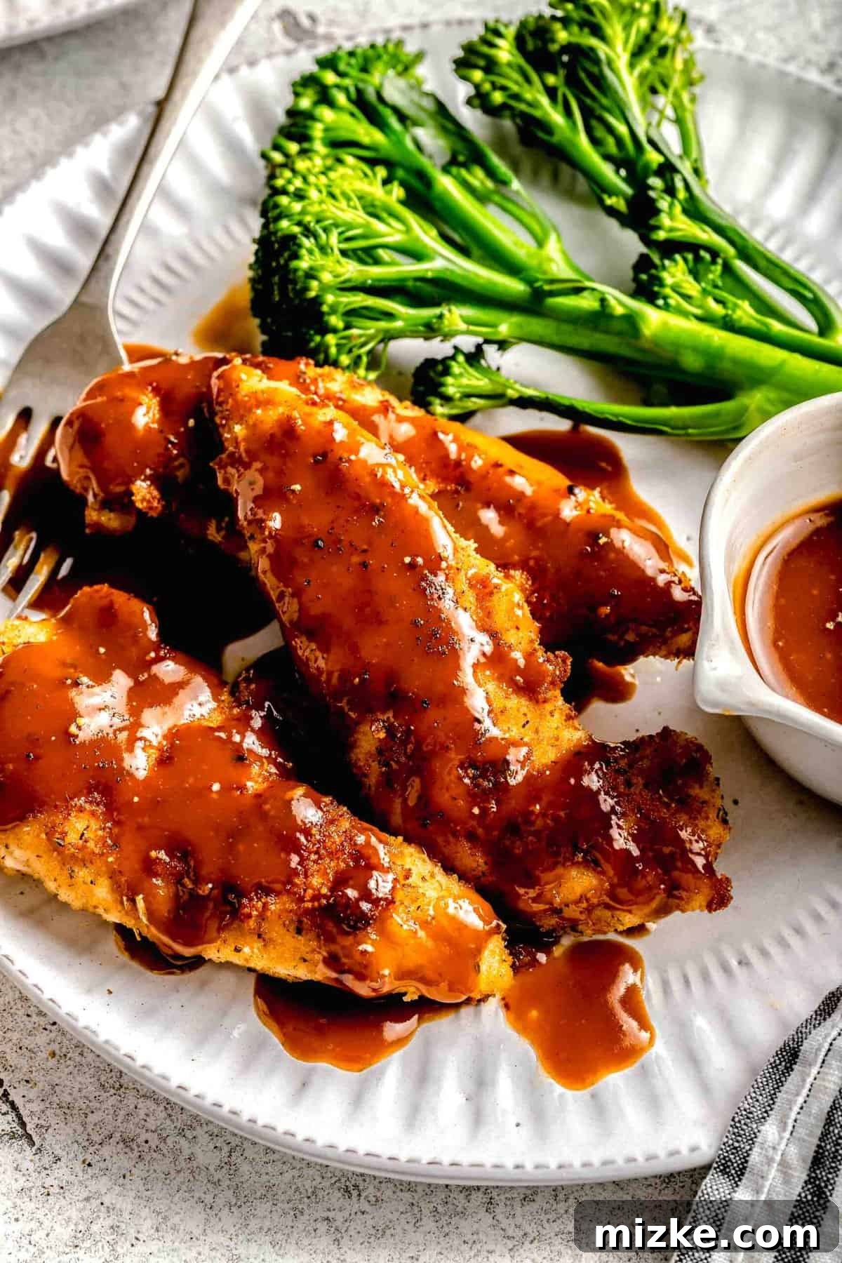 The ultimate comfort food: golden-brown bourbon chicken generously coated in sauce, ready to be enjoyed. Another close-up of bourbon chicken on a plate with broccoli, showing the glistening sauce and crispy chicken texture.