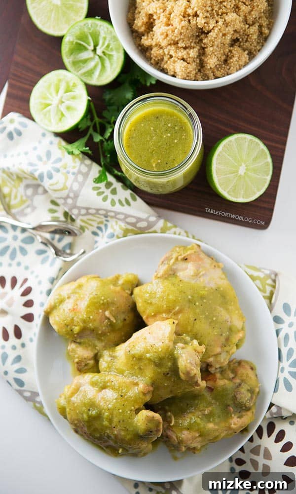 Slow cooker salsa verde chicken on a plate next to vibrant homemade salsa verde, fresh lime wedges, and a bowl of fluffy quinoa.