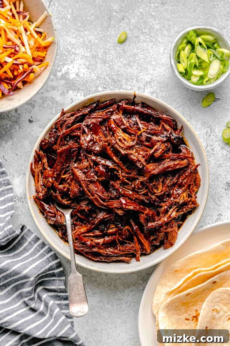 Slow Cooked Korean BBQ Pork Tacos 3 A white bowl brimming with perfectly shredded, tender Korean pork, showcasing its rich, savory glaze.