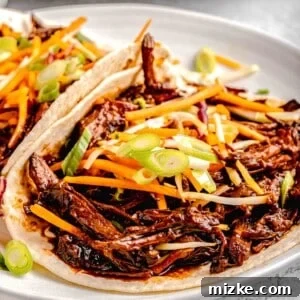 A white plate featuring two perfectly assembled Korean pork tacos, showcasing the vibrant ingredients.