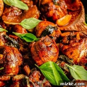 Closeup of three cup chicken in skillet with basil leaves