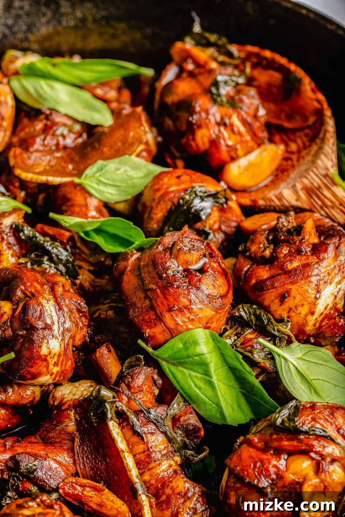 This authentic Taiwanese recipe for three cup chicken (三杯雞) is easy enough to make at home, so you won't have to get it from a restaurant! Closeup of three cup chicken in skillet with basil leaves.