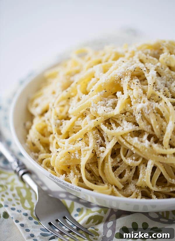 Cacio e Pepe: The Classic Roman Cheese and Pepper Pasta Dish, Rich, Creamy, and Incredibly Easy to Make A bowl filled with Cacio e Pepe, topped generously with grated Pecorino Romano cheese and coarse black pepper, resting next to a fork on a textured placemat. The pasta glistens with a creamy sauce.