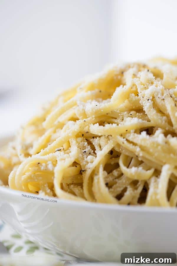 A Delicious Close-Up of Authentic Cacio e Pepe with Parmesan and Black Pepper Close-up shot of a steaming bowl of Cacio e Pepe, beautifully garnished with a generous sprinkle of grated Parmesan cheese and freshly cracked black pepper. The pasta strands are perfectly coated in a creamy, glossy sauce.