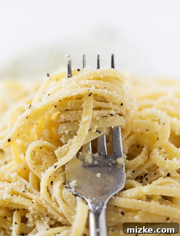 The Perfect Bite: Cacio e Pepe on a Fork Close-up of a fork expertly twirled with Cacio e Pepe spaghetti, showcasing the creamy sauce, flecks of black pepper, and grated Parmesan cheese clinging to every strand.