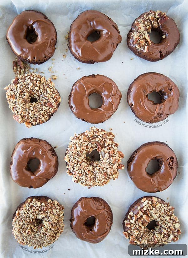 Cooling Freshly Fried Chocolate Donuts Several chocolate chocolate donuts cooling on a wire rack over paper towels, waiting for their chocolate ganache glaze