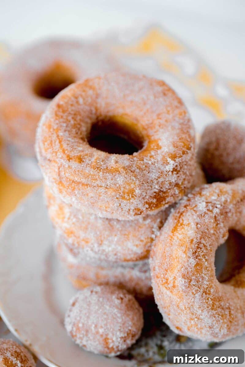 Effortless Biscuit Donut Bliss 3 biscuit sugared donuts stacked on a plate with donut holes