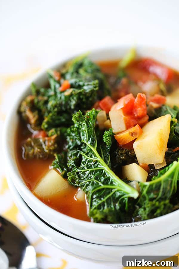 Tomato, kale, and potato soup is a perfectly hearty and healthy soup that is chock full of veggies! A vibrant bowl of hearty Tomato, Kale, and Potato Soup, garnished with fresh herbs, perfect for a cozy meal.
