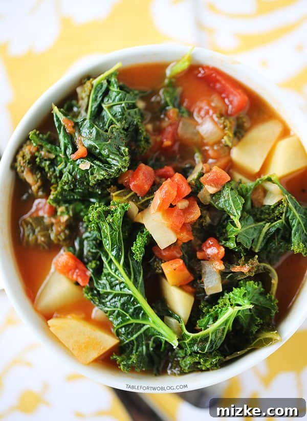 Tomato, kale, and potato soup is a perfectly hearty and healthy soup that is chock full of veggies! A serving of comforting Tomato, Kale, and Potato Soup in a rustic bowl, garnished with a sprinkle of cheese.