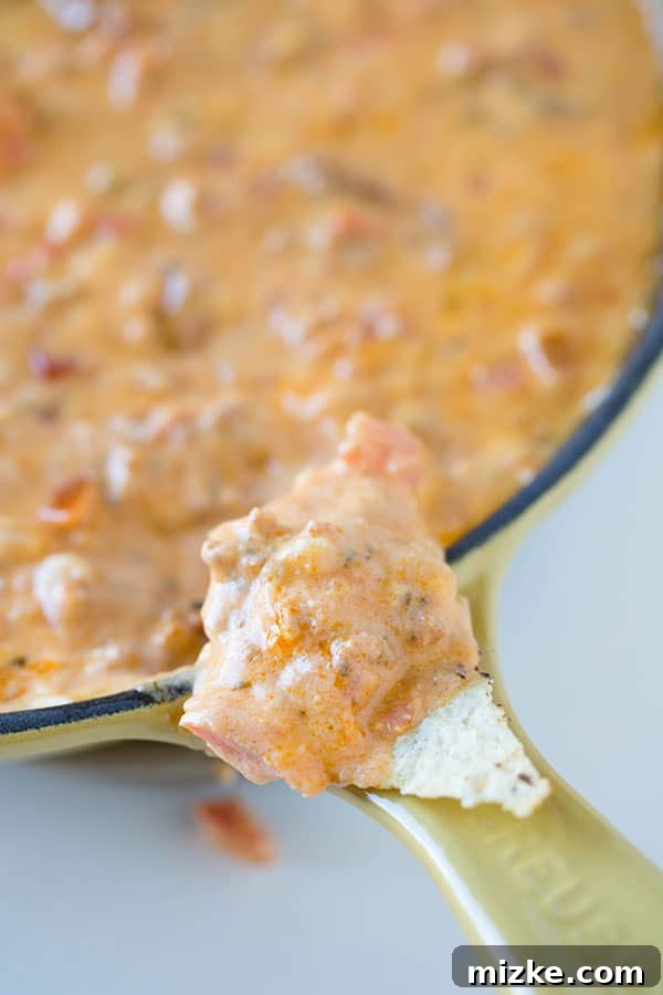 Make this Chorizo Pimento Cheese Dip for your next game day or casual get-together! Another close-up of the warm, cheesy Chorizo Pimento Cheese Dip with a spoon, inviting guests to dig in.
