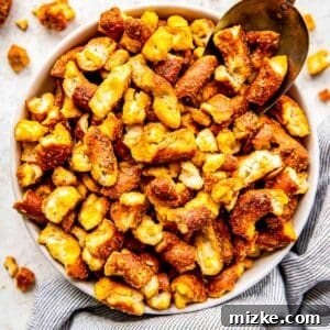 Tangy Gold Pretzel Crunch 10 A scoop is placed in a bowl of honey mustard pretzels, highlighting their irresistible golden coating.