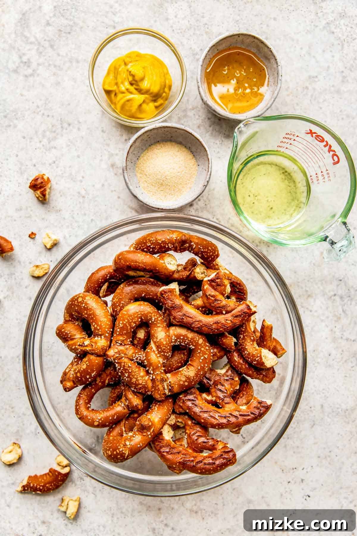 Tangy Gold Pretzel Crunch 3 The essential ingredients for making honey mustard pretzels are beautifully arranged on a kitchen counter, highlighting their simplicity.