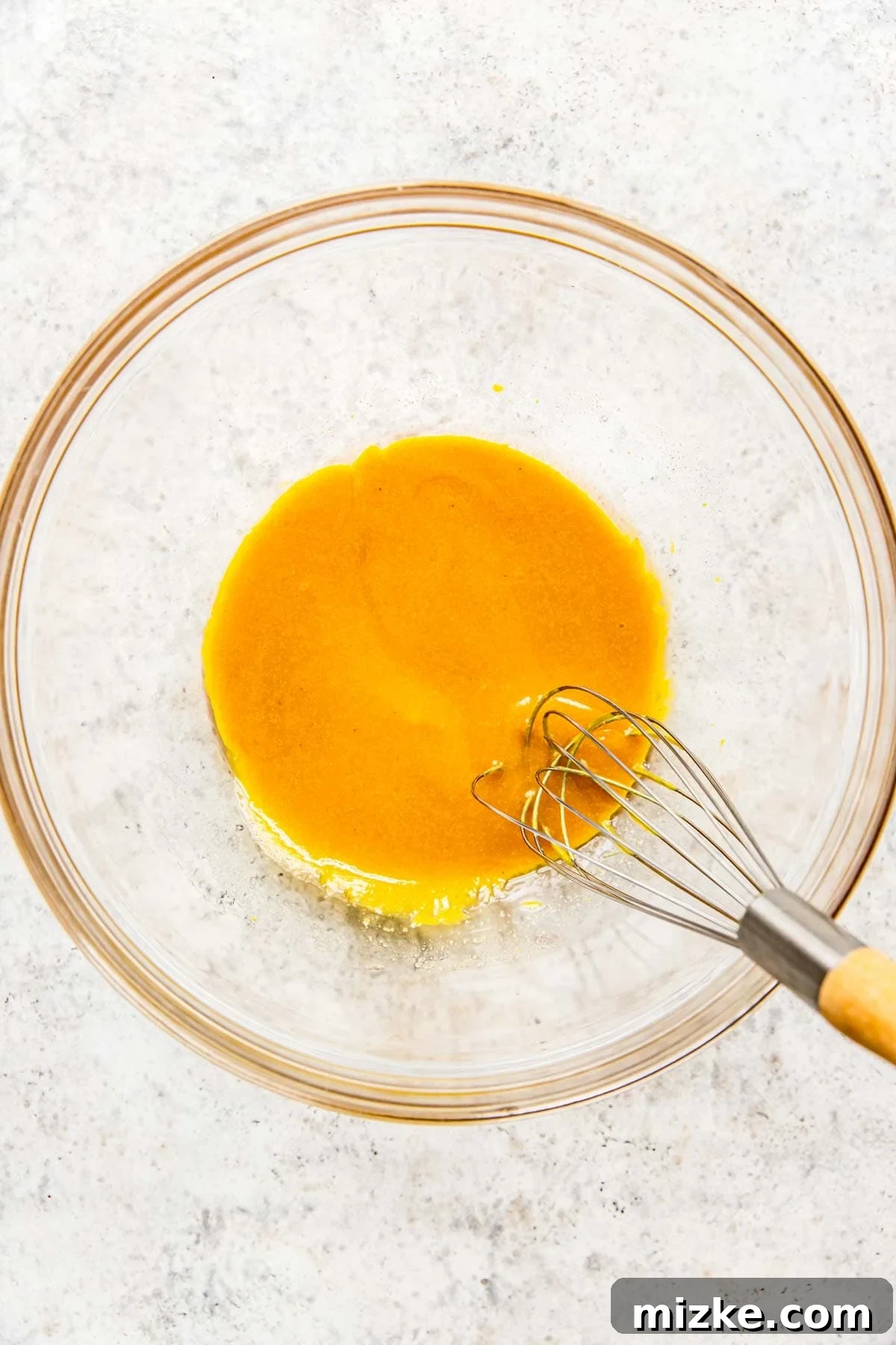 Tangy Gold Pretzel Crunch 5 A whisk smoothly blends the honey mustard ingredients in a glass bowl, creating a perfect, uniform sauce.