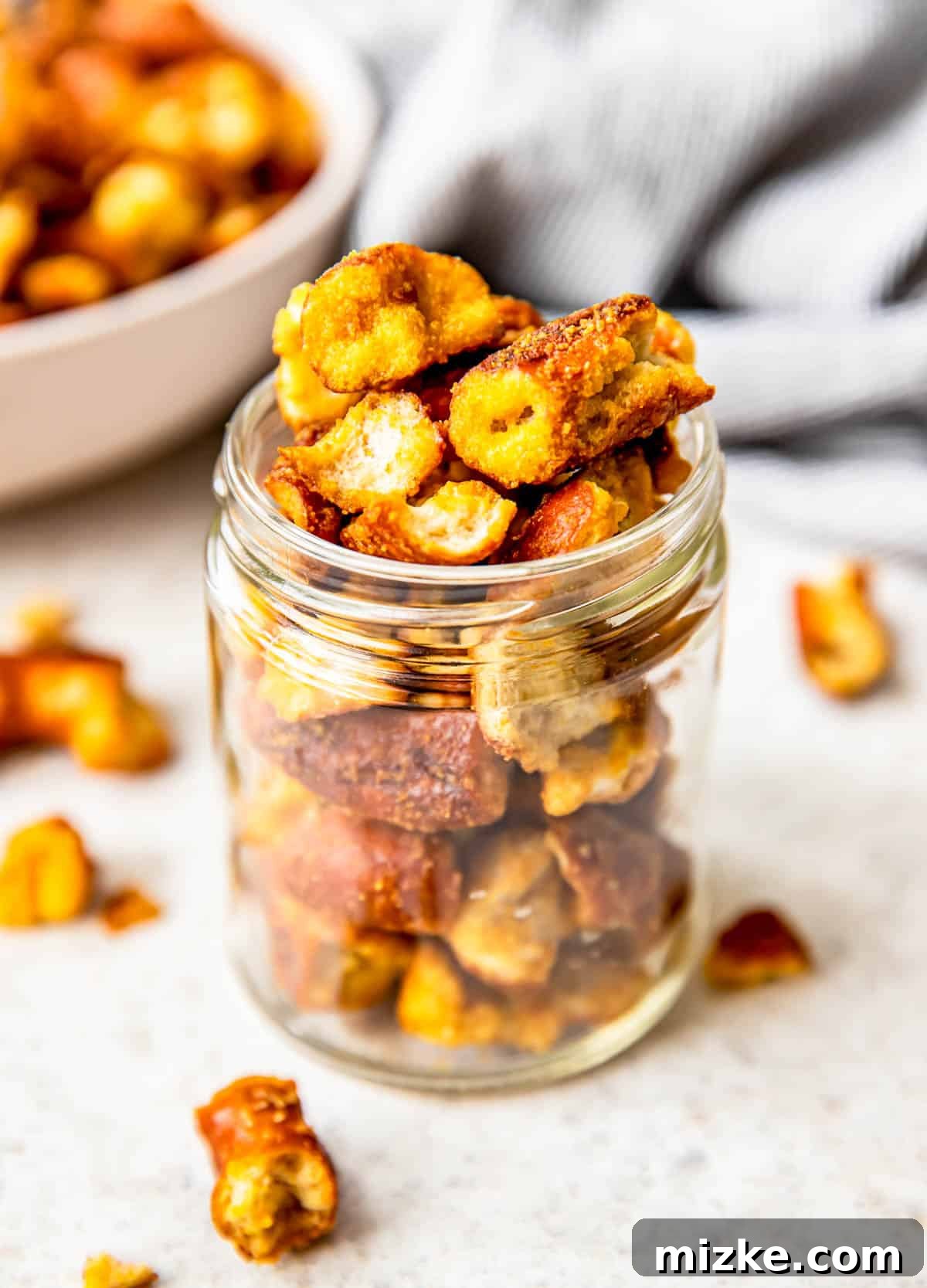 Tangy Gold Pretzel Crunch 8 A charming small glass jar is filled to the brim with perfectly seasoned honey mustard pretzels, ideal for gifting or immediate enjoyment.