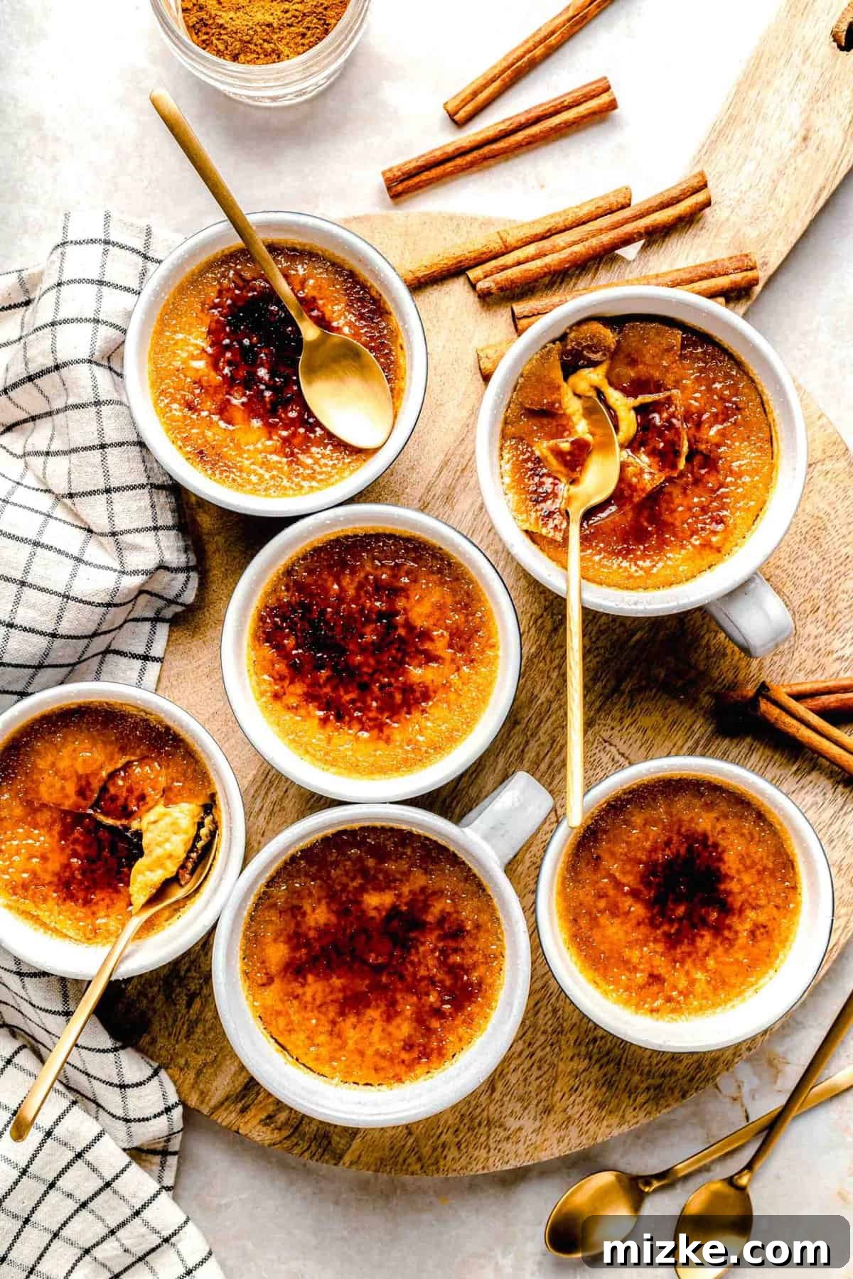Creamy, restaurant-quality pumpkin creme brulee is infused with just the right amount of pumpkin & has the perfect caramelized sugar topping. Overhead shot of several ramekins of golden pumpkin creme brulees, some with caramelized tops and some without.