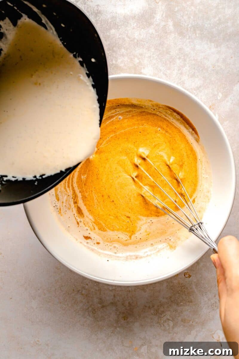 Creamy, restaurant-quality pumpkin creme brulee is infused with just the right amount of pumpkin & has the perfect caramelized sugar topping. Warm heavy cream being slowly whisked into a light orange pumpkin custard mixture in a glass bowl.