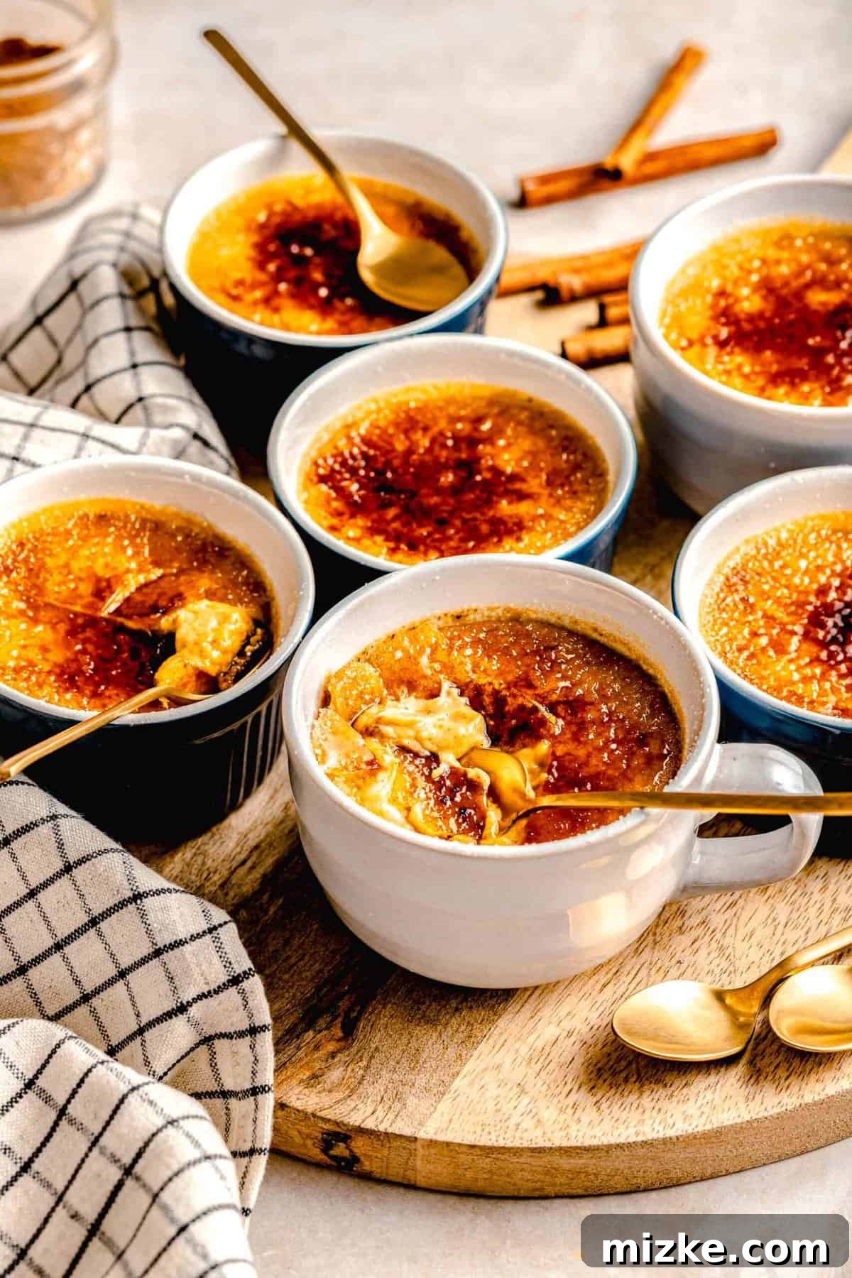 Creamy, restaurant-quality pumpkin creme brulee is infused with just the right amount of pumpkin & has the perfect caramelized sugar topping. Several ramekins of perfectly caramelized pumpkin creme brulee arranged on a rustic wooden serving board.