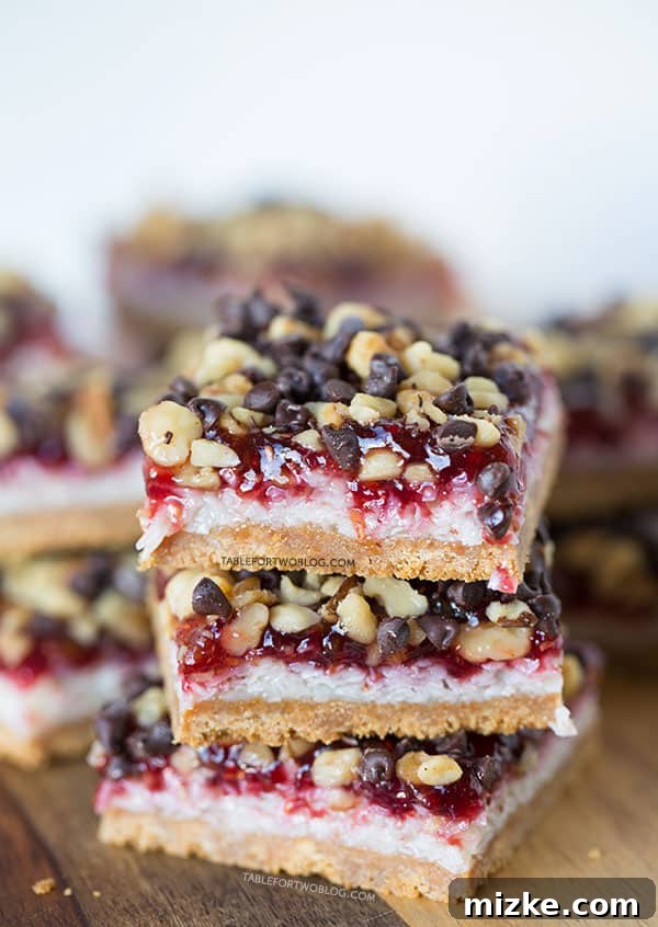 Delicious raspberry coconut bars cooling on a wire rack, ready to be sliced, showcasing layers of jam, coconut, and crust.