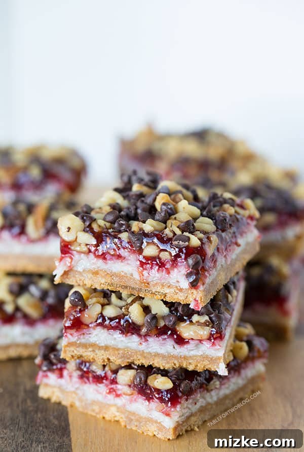 Close-up shot of a single raspberry coconut bar, revealing the rich texture of coconut, a vibrant layer of raspberry jam, and a sturdy graham cracker crust.