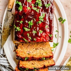Sliced classic meatloaf on a plate with a knife, showcasing its moist texture and rich glaze.