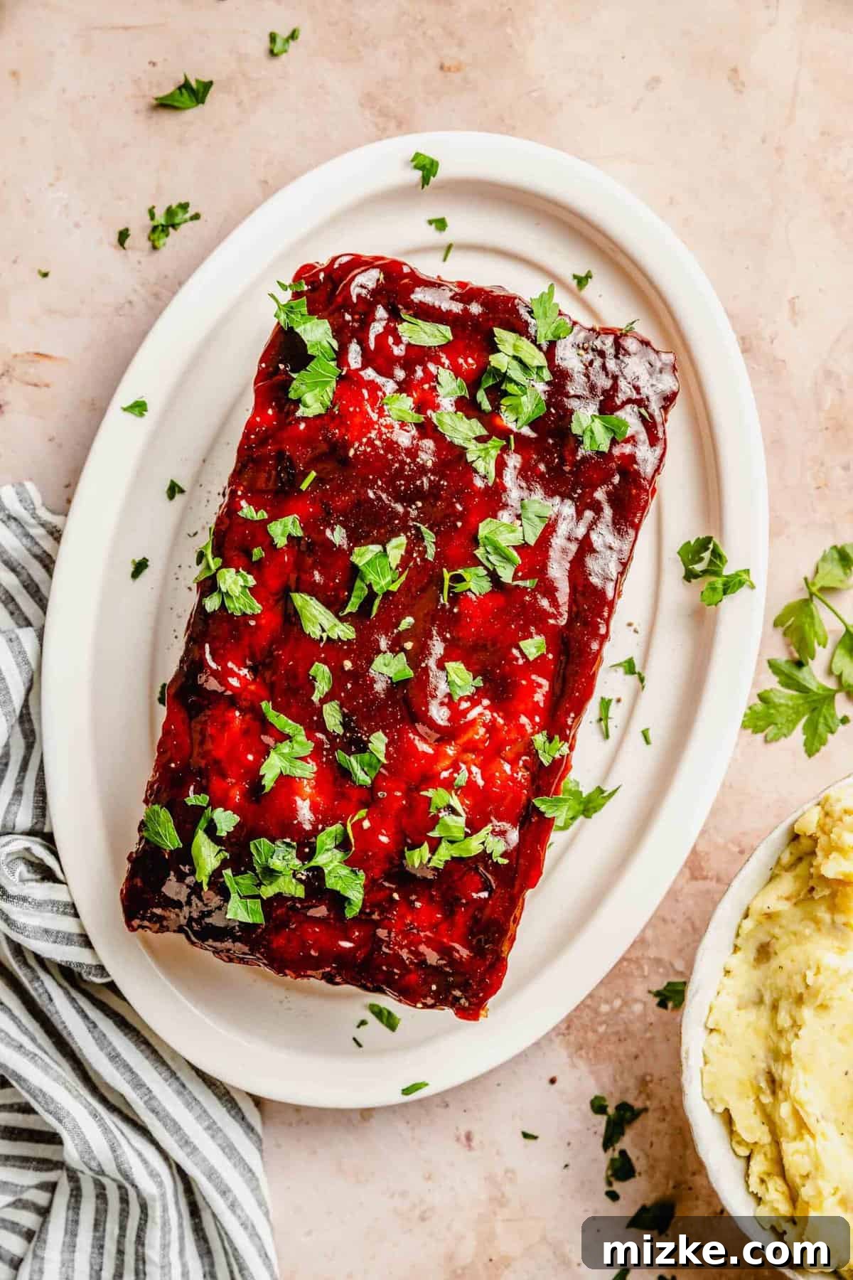 This perfectly baked classic meatloaf is the ultimate easy weeknight meal. Moist, delicious, and coated in a sweet and tangy sauce, it's a must-try comfort food! A whole classic meatloaf, perfectly glazed, resting on a serving plate, ready to be enjoyed.