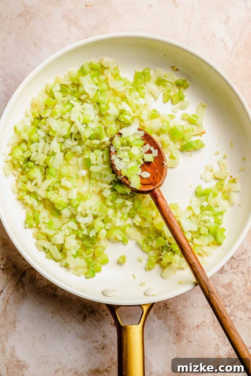 Sauté fresh onions, celery, and garlic until tender – a crucial step for building deep flavor in your classic meatloaf. Diced onions, celery, and minced garlic sautéing in a skillet, softening to release their aromas.