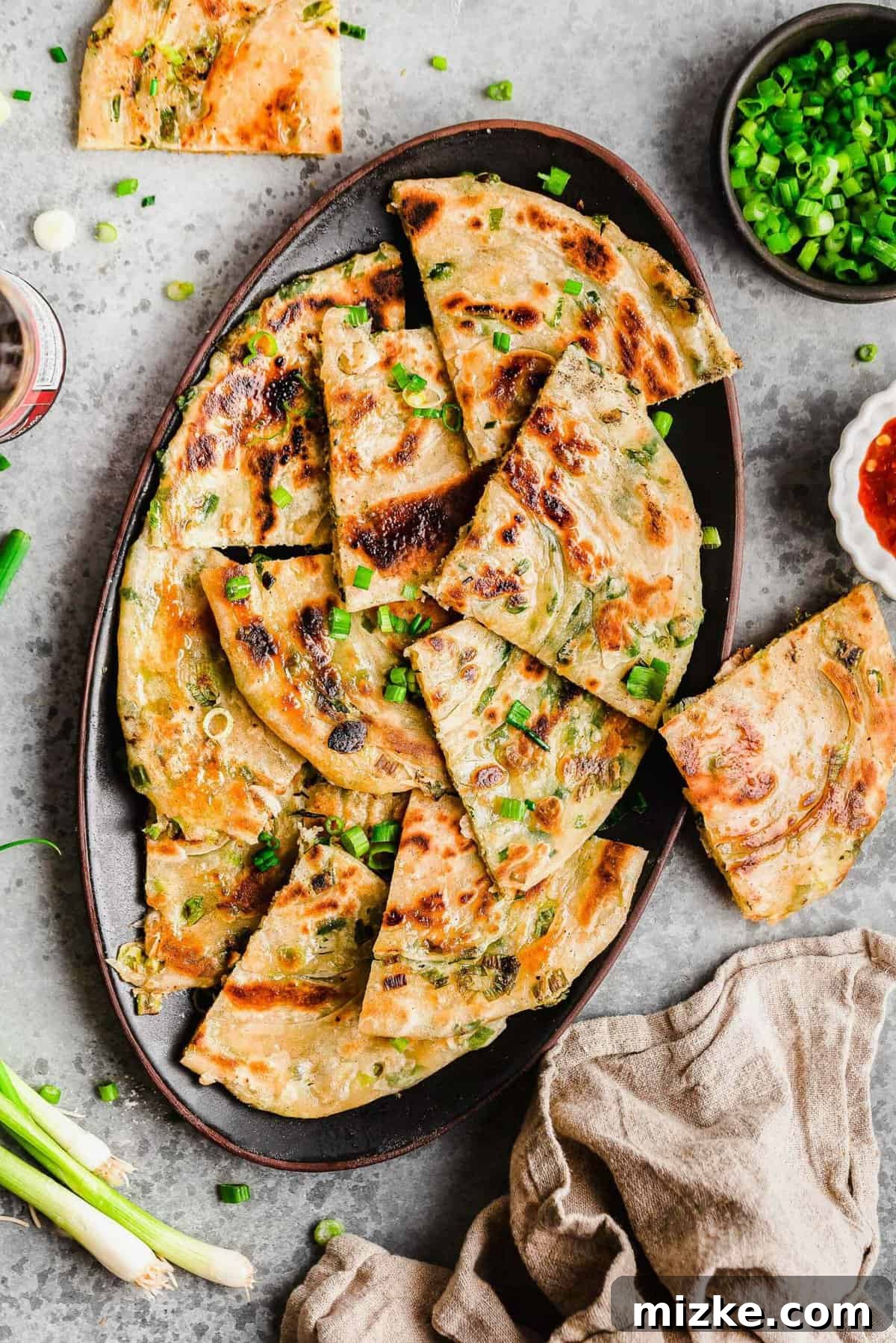 Freshly cooked scallion pancakes ready to be enjoyed, showcasing their crispy texture and aromatic green onion topping. An inviting overhead view of golden-brown scallion pancakes arranged on a platter, garnished with fresh chopped scallions for a vibrant finish.