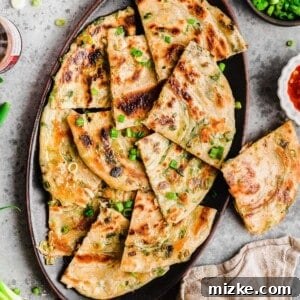 Overhead view of scallion pancakes on a platter with scallions scattered over the top.