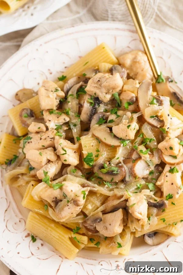 Creamy Marsala Chicken Rigatoni with Mushrooms 2 A close-up shot of creamy chicken rigatoni and mushroom marsala pasta, garnished with fresh parsley and Parmesan cheese, evoking a sense of rich comfort food.