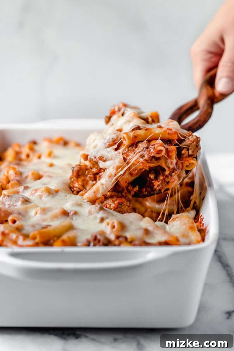 Ultimate Baked Ziti 2 Hearty Baked Ziti with golden-brown cheese topping and fresh basil garnish, served on a rustic wooden table