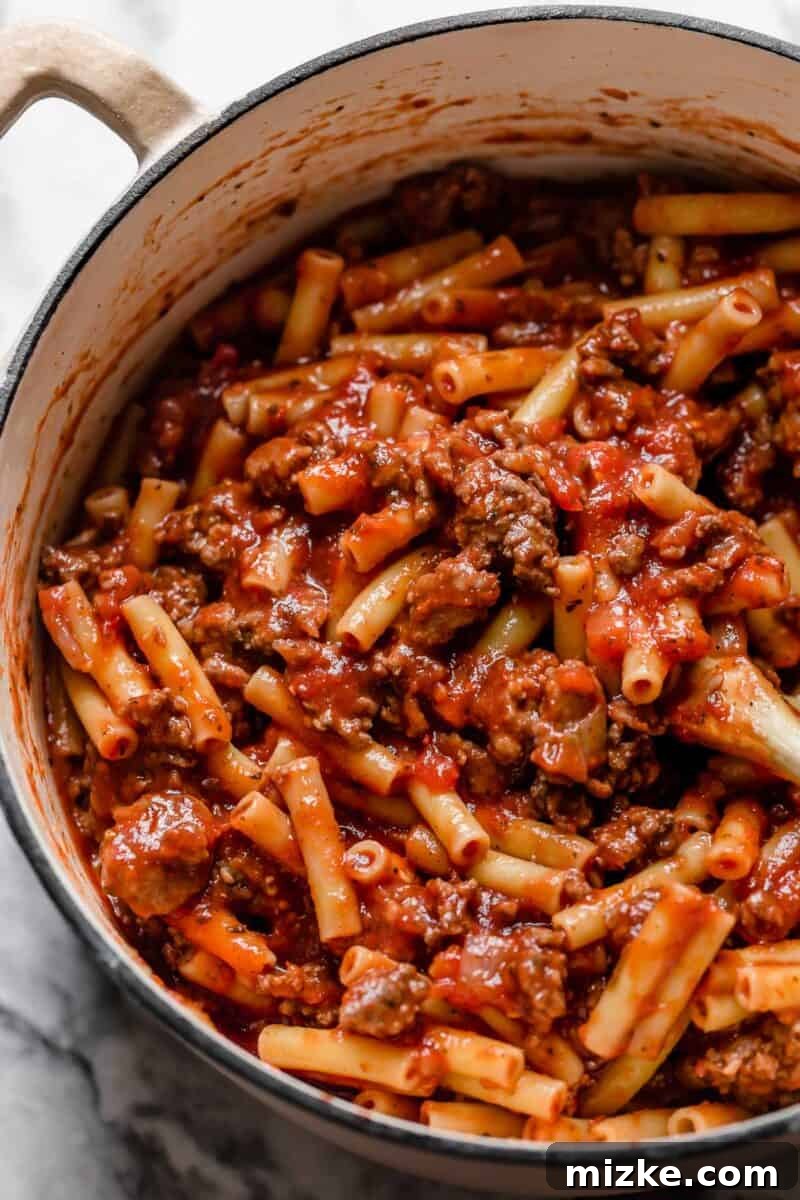 Ultimate Baked Ziti 5 A serving of classic Baked Ziti being scooped, showcasing a decadent cheese pull and rich pasta