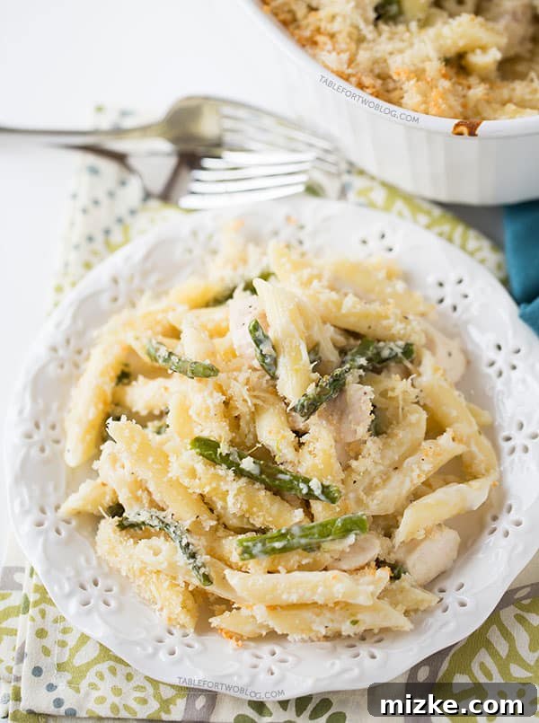 Preparing the delicious spring-inspired penne bake with fresh asparagus. Overhead shot of the Roasted Asparagus and Chicken Penne Bake in a casserole dish before baking.