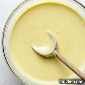 Pistachio ice cream base in a bowl with a wooden spoon.