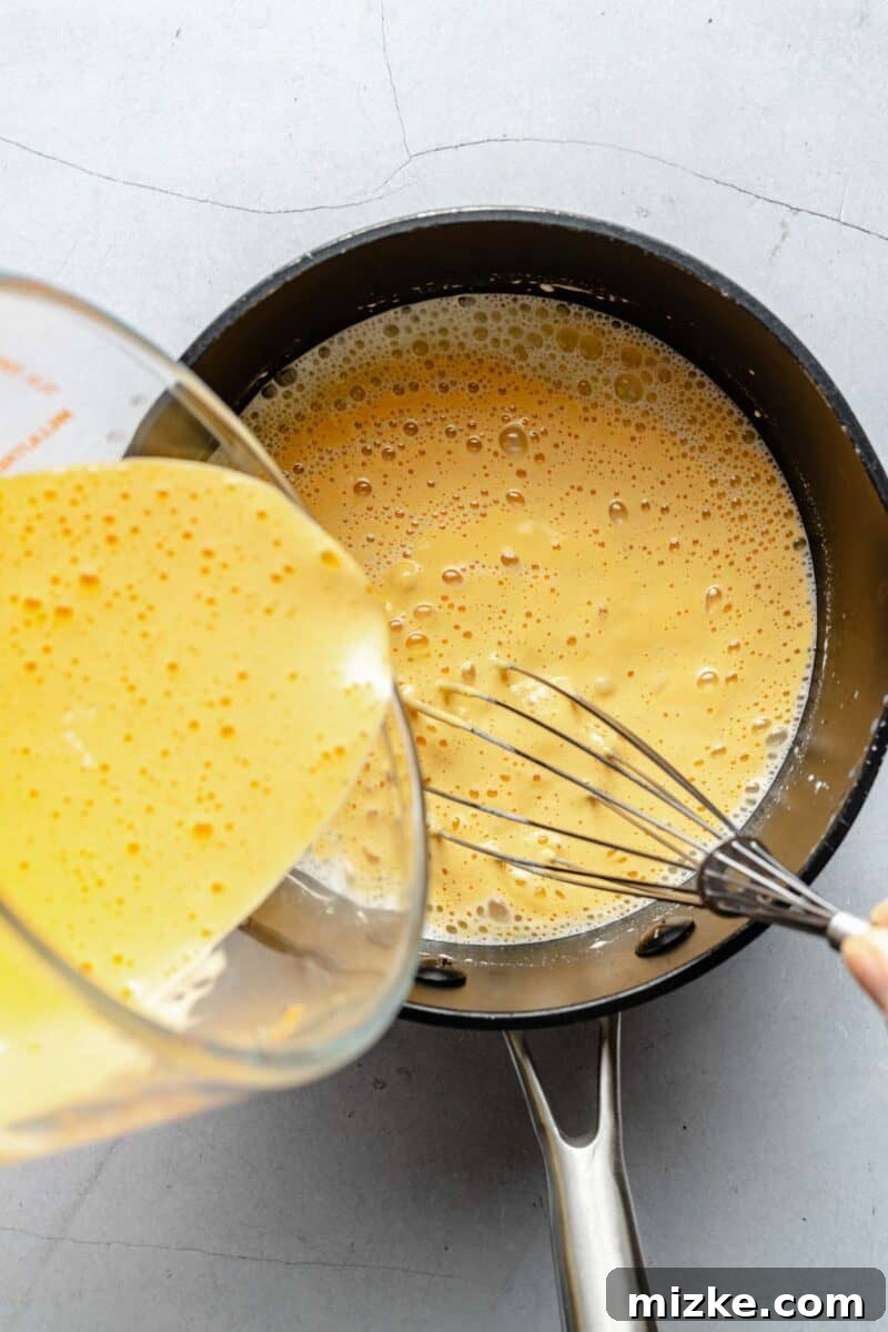 Velvet Pistachio Dream 5 Whisking tempered egg yolks into the warm custard mixture for ice cream.