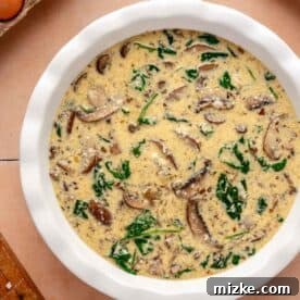 egg and mushroom spinach mixture added to a white baking dish