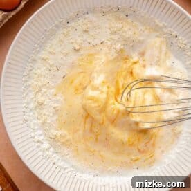 whisking together egg mixture in a white bowl