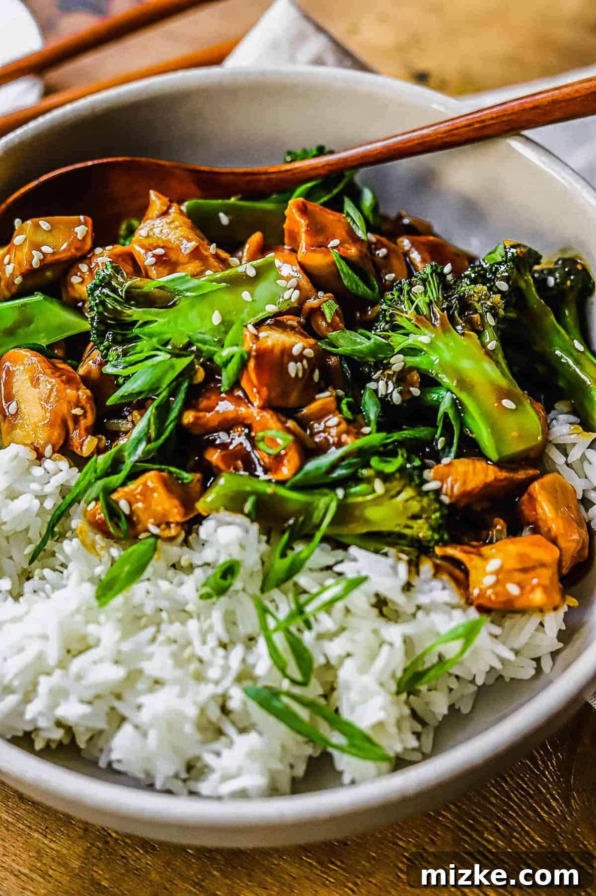 This 20-minute teriyaki chicken and broccoli recipe is made with juicy chicken and tender broccoli. It's healthy and better than takeout! close up of white bowl filled with rice and teriyaki chicken and broccoli