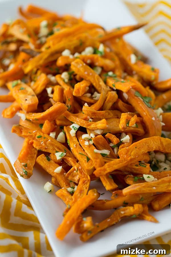 Baked Garlic Sweet Potato Fries: A perfect healthy side dish for any meal. Recipe on tablefortwoblog.com Crispy baked garlic sweet potato fries served in a bowl, ready to be enjoyed as a healthy side dish or snack. Recipe on tablefortwoblog.com