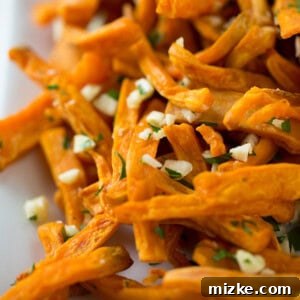 Close-up of baked garlic sweet potato fries in a white bowl.