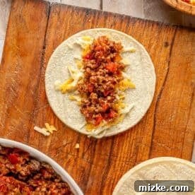 Savory Beef Enchiladas 14 a corn tortilla with shredded cheese and ground beef mixture in the center