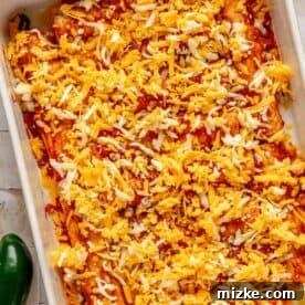 Savory Beef Enchiladas 16 beef enchiladas in a baking dish with red enchilada sauce and shredded cheese sprinkled on top
