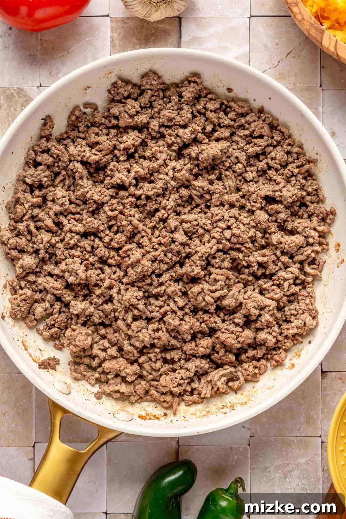 Savory Beef Enchiladas 3 Ground beef and diced onions browning in a white nonstick skillet, ready for seasoning.
