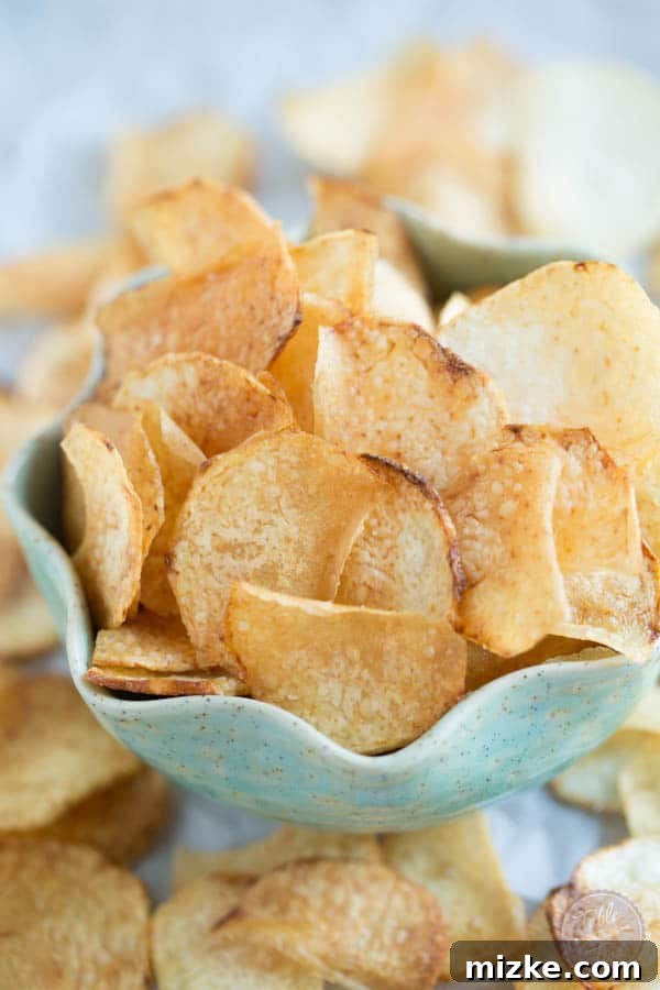 Sliced taro chips frying in hot oil, bubbling and turning a golden brown.