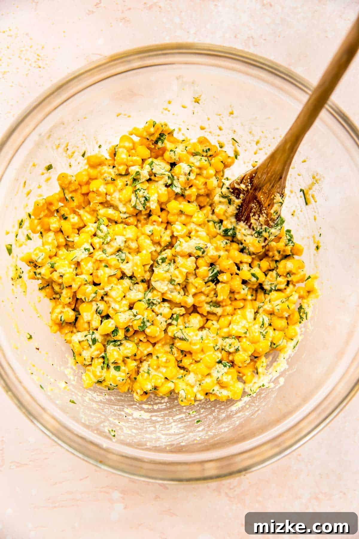 Smoky Sweet Corn Bites 6 A wooden spoon gently stirs the corn fritter batter, ensuring the corn kernels are evenly coated and well-incorporated.