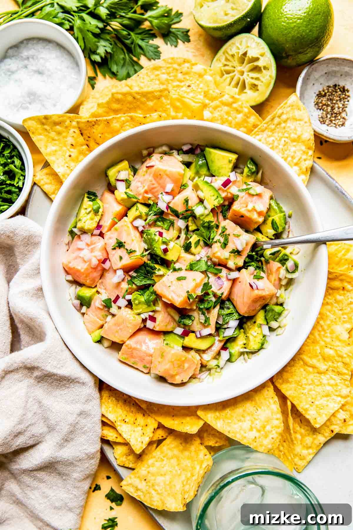 Zesty Salmon Ceviche 2 A bowl of vibrant salmon ceviche, garnished with fresh herbs and surrounded by crispy tortilla chips and fresh limes, ready to be enjoyed.