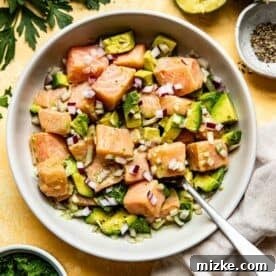 A bowl of salmon, avocado, and shallots mixed together, showing the salmon's color changing as it cures.